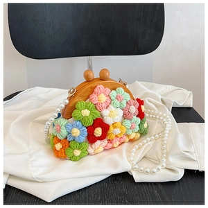 Detail of hand-woven shell bag with colorful crochet flowers and pearl chain strap