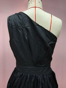 Detail of black one-shoulder satin dress showing fabric texture and shoulder design