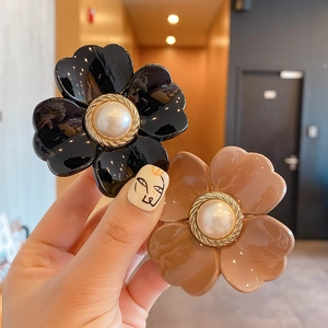 Detail of flower hair claws with large central pearls and elegant golden woven edges