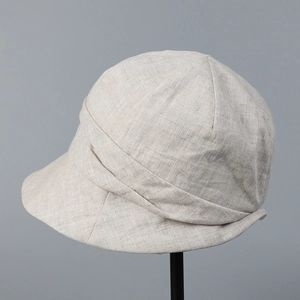 Détail macro du lin respirant et du ruban superposé sur le chapeau cloche beige