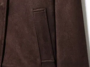 Détail d'une poche passepoilée verticale sur une veste en daim synthétique marron foncé