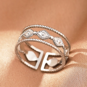 Macro shot of silver-colored triple-layer braided adjustable ring on gold silk background