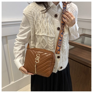 Detailed macro of brown quilted leather bag with CS metallic logo and tassel decor