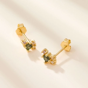 Macro shot of S925 sterling silver gold earrings with green faceted gemstone and zircons
