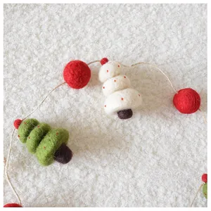 Detail von handgemachten Wollfilz-Weihnachtsbäumen und Kugeln auf weißem Texturhintergrund