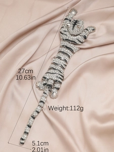 Detail of silver tiger brooch with black enamel and rhinestones on champagne silk fabric