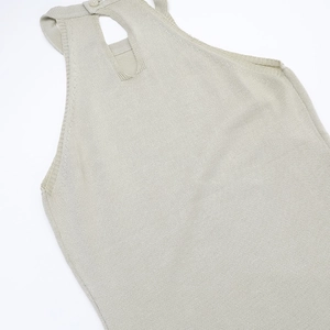 Detail van de halterhals met elegante uitsnijding en knoopsluiting op de beige gebreide jurk