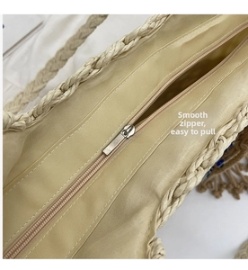 Detail view of woven straw tote bag featuring smooth metal zipper and beige fabric lining