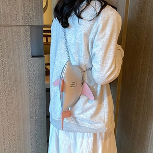 Silver shark-shaped crossbody bag with pink fins and metal chain strap shown on model