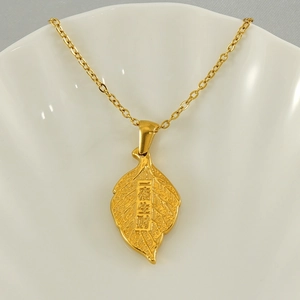 Gold leaf pendant necklace with lucky engraving on a white ceramic plate