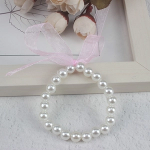 Close-up of a white imitation pearl bracelet for girls featuring a pink ribbon bow accent