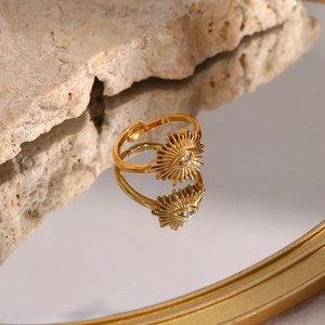 Detail of 18K gold-plated evil eye ring with sunburst design and zircon on stone background
