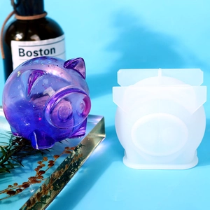 Macro view of a 3D pig silicone mold next to a purple glitter resin handicraft figure