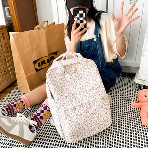 Detailed view of floral canvas backpack featuring a front pocket and sturdy top handles