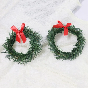 Pair of festive green PVC Christmas pine wreaths with elegant red bows on white fur