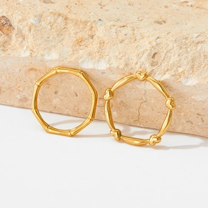 Golden heart and bamboo style stainless steel rings on a natural stone background