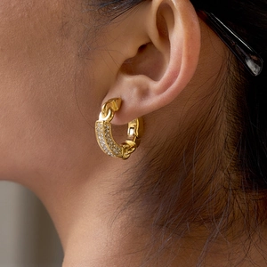 Gold chain-link hoop earrings with sparkling zircon inlay shown on model's ear