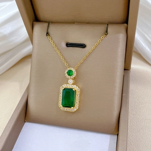 Close-up of a gold necklace with a rectangular green emerald and pavé diamond halo