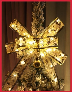 Close-up of golden LED Christmas ribbon bow with warm white lights and star patterns