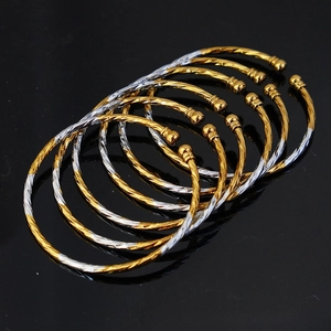 Detail view of 3mm gold and silver twisted rope bangles with bead ends and carved texture