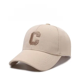 Close-up of beige baseball cap featuring brown 3D embroidered C letter on textured fabric