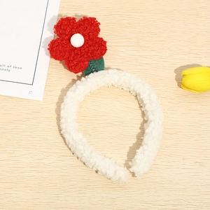 Detailed view of red plush tulip headband on a rustic wooden background with flowers
