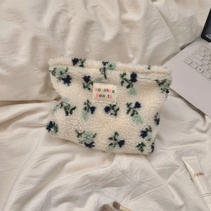 Detail of plush floral cosmetic bag showing soft fleece texture and brand woven label