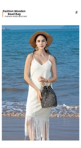 Detail of hand-woven wood bead bucket bag with bamboo handles on a sunny beach