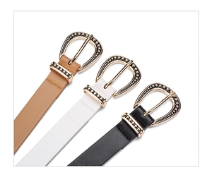 Detailed shot of retro horseshoe buckles in gold with embossed dots on slim leather belts