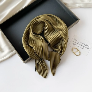 Detailed texture of olive green pleated silk scarf displayed on a black tray