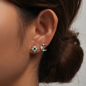 Macro detail of asymmetric 925 silver stud earrings with green zircon star and moon design