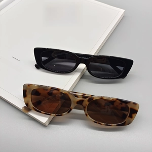 Fashionable square frame sunglasses in black and tortoise shell finish on a white book