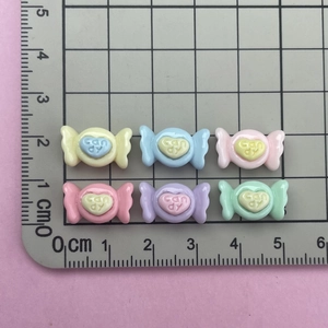 Close-up of six colorful resin candy charms with heart center and CANDY text for DIY