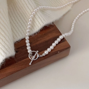 Close-up of 925 silver OT clasp and pearls on a brown wooden block and knit fabric