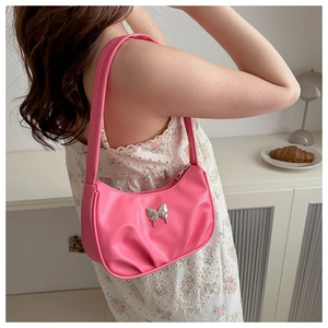 Detail of pink vintage underarm bag with silver butterfly buckle on model shoulder