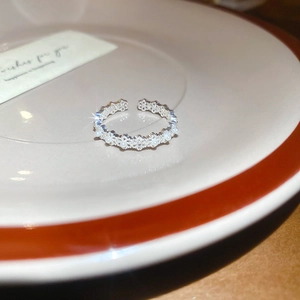 Macro shot of silver lace flower ring with pearls on elegant ceramic plate