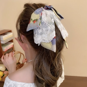Detail of floral fabric and embroidered lace bow hair clip with intricate hollow patterns