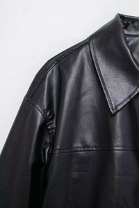 Close-up of black faux leather bomber jacket collar and shoulder stitching details