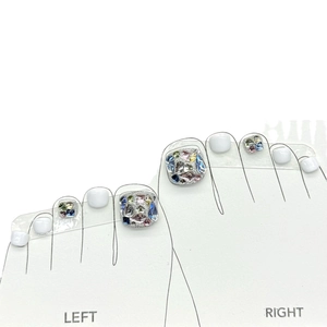 Sparkly white press-on toenails with colorful rhinestone accents for a DIY pedicure look