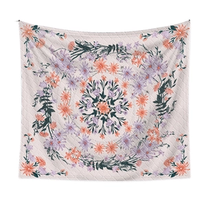 Detail of pink bohemian tapestry featuring purple floral patterns and quilted diamond texture