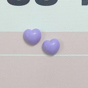 Close-up of two purple glossy resin heart charms for phone cases and DIY crafts