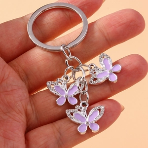 Close-up of silver butterfly keychain with purple enamel and sparkling rhinestones