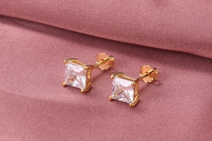 Macro detail of S925 silver stud earrings with square princess cut zircon on pink fabric