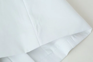 Close-up of white woven cotton fabric with detailed stitching and clean texture