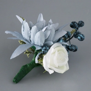 Détail d'une boutonnière faite main bleu clair avec roses blanches et baies foncées