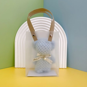 Frosted gift bag with a blue plush bear towel, pearl bow, and brown paper handles