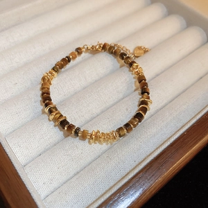 Detailed macro view of tiger eye beads and heart charm on a golden beaded bracelet