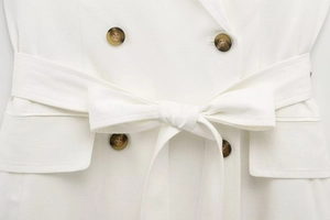 Détail de la robe blazer blanche montrant la texture du coton et le bouton en écaille