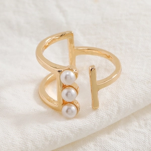 Minimalist gold geometric open ring featuring three white linear pearls on knit background