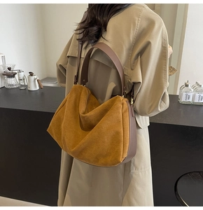 Brown suede hobo bag shown on shoulder in a cafe setting with vintage baguette style